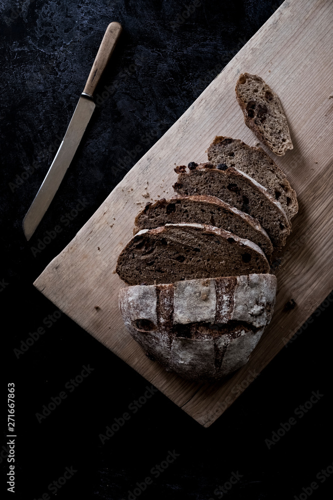 A loaf of fresh sliced brown bread on a bread board and a sharp knife A loaf of fresh sliced brown bread on a bread board and a sharp knife