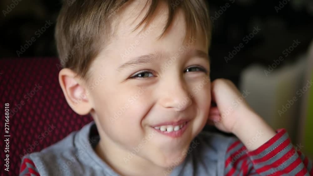 The boy, who looks into the distance, smiles and holds his hand behind his ear. Happy child shows joyful emotions The boy, who looks into the distance, smiles and holds his hand behind his ear. Happy child shows joyful emotions