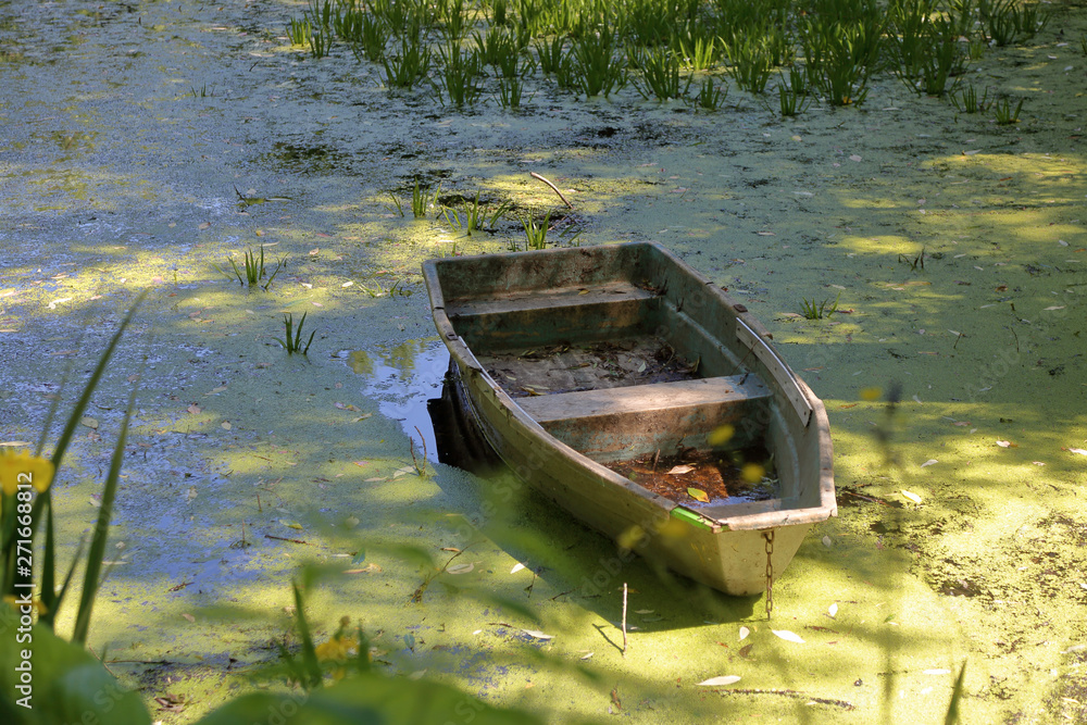 Old abandoned iron boat in a duckweed pond