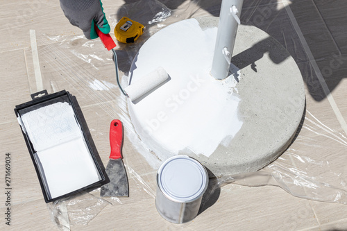 Cleaning and painting job of sun umbrella base. Concept of small scale repair and renovation jobs at home. Concept of preparing for the summer season.