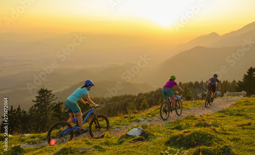 LENS FLARE: Four young travelers ride their mountain bikes downhill at sunrise.