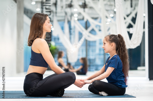 Young adult mother and little daughter together practicing yoga