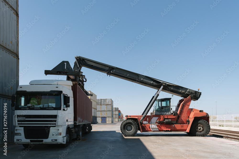 Crane lifting cargo container on truck on industrial site Crane lifting cargo container on truck on industrial site