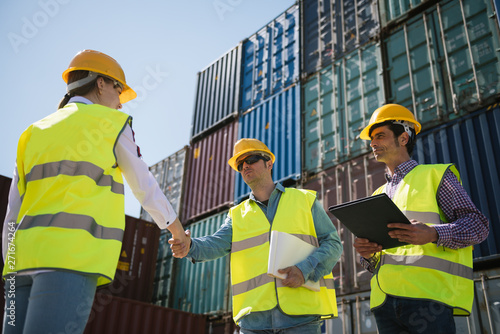 Workers shaking hands in front of cargo containers on industrial site photo