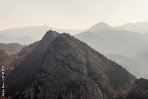 Soft hazy view of impressive rocky mountains and distant mountain silhouettes photo
