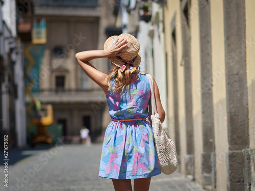 Cute European girl in sunhat is walking along the city. She is enjoying her summer holidays.
