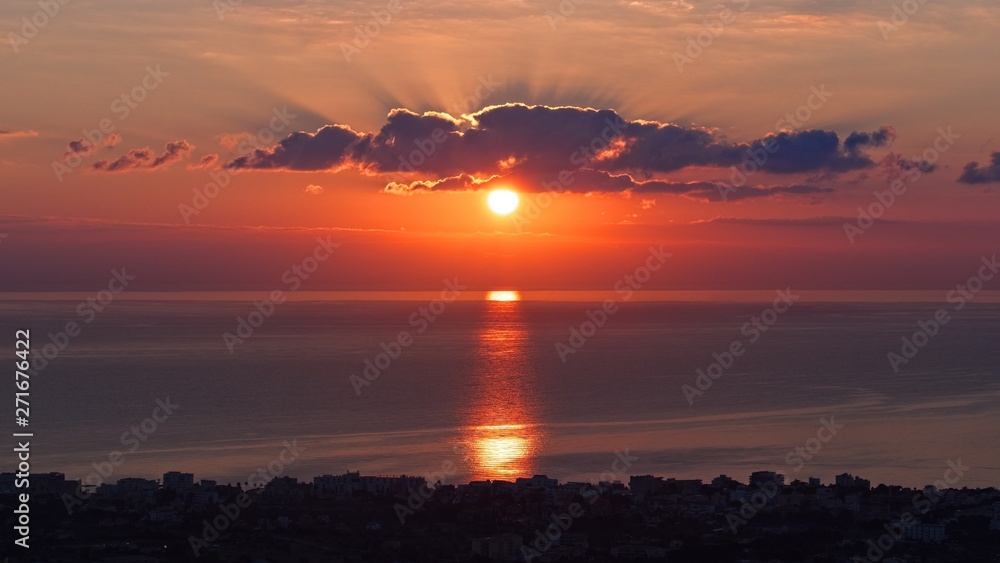 Sunrise in cala millor, red fiery dramatic sky above mediterranean sea, mallorca, spain.