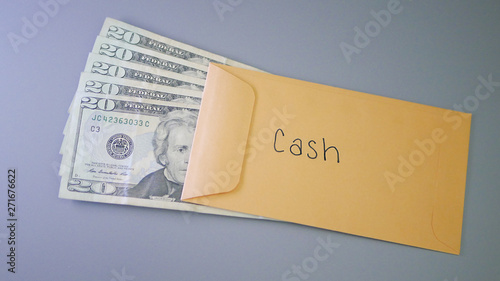 A yellow envelope on a gray table, containing cash for cash savings.