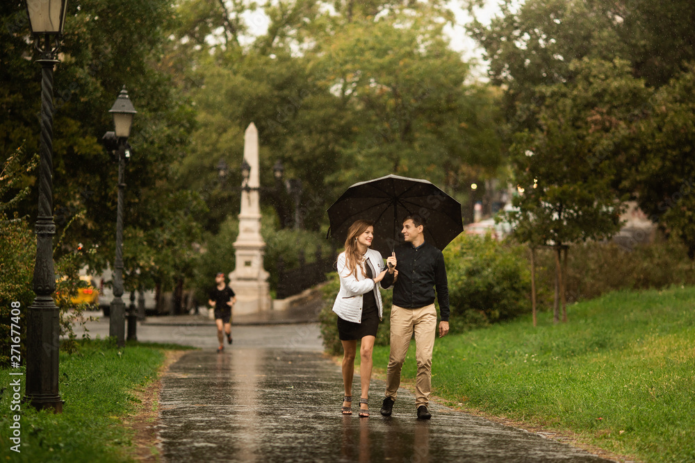 Young couple walking in the park on a rainy day. Love story in Budapest