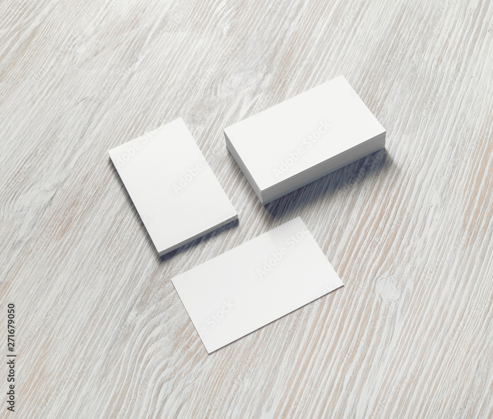 Blank white business cards with soft shadows on light wooden background. For design presentations and portfolios. Blank white business cards with soft shadows on light wooden background. For design presentations and portfolios.