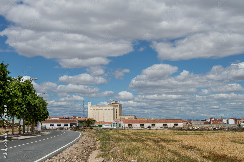 View of a field and a road with buildings and a silo in Torrijos, province of Toledo. Castilla la Mancha. Spain