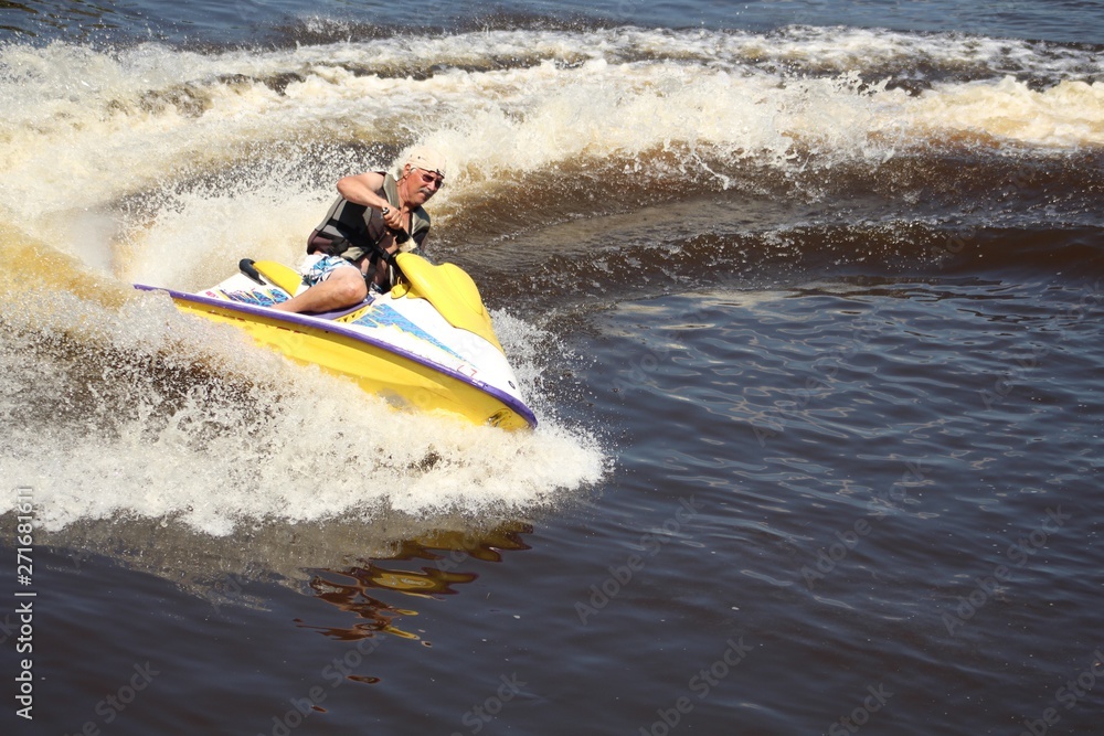 active senior man riding personal watercraft wearing life jacket personal flotation device