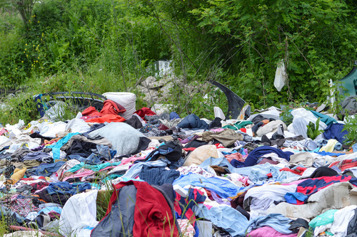 Garbage dump in nature. Environmental pollution. Abandoned clothes in nature photo