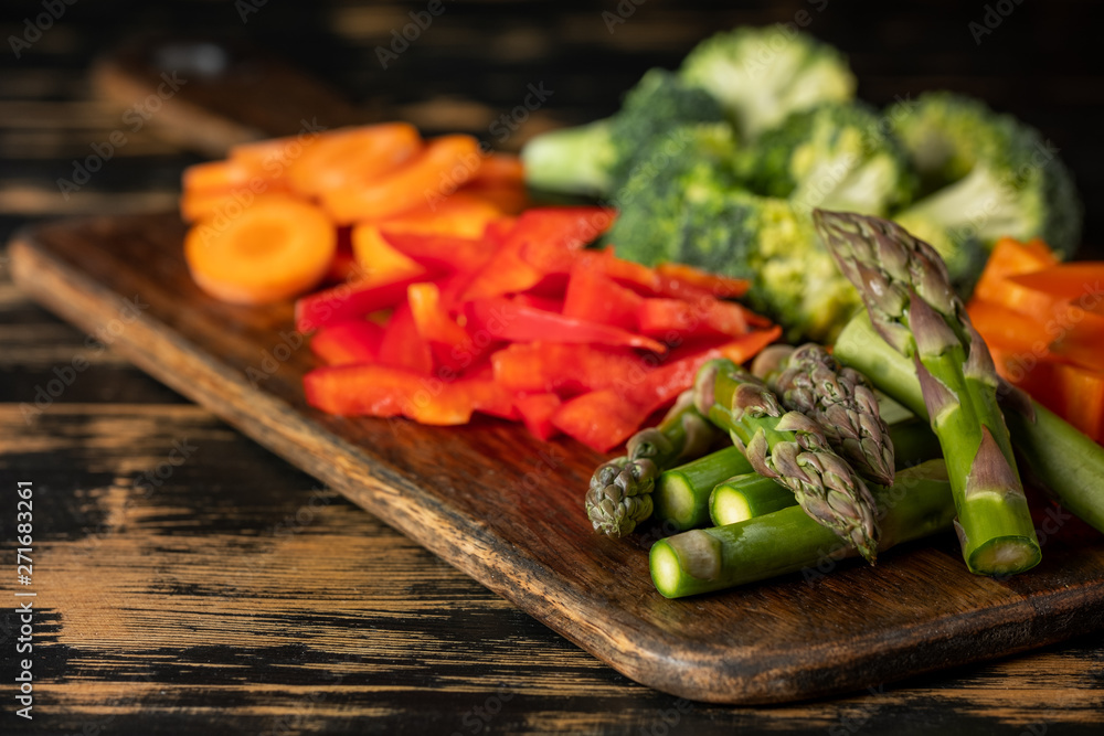 Raw vegetables cooking - carrot, paper, asparagus, broccoli and greens on wooden table background. Raw vegetables cooking - carrot, paper, asparagus, broccoli and greens on wooden table background.
