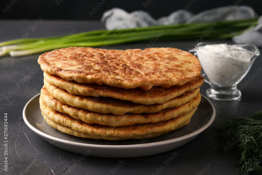 Homemade tortillas, located on a plate on a dark background, pictured green onions and sour cream Homemade tortillas, located on a plate on a dark background, pictured green onions and sour cream