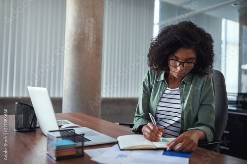 Fotografia Businesswoman writing in an agenda on a desk at office