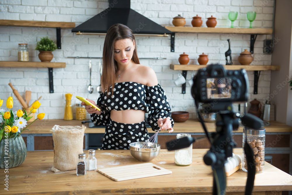 Pretty young woman girl food blogger in polka dot dress working on a new video and explaining how to cook a dish Pretty young woman girl food blogger in polka dot dress working on a new video and explaining how to cook a dish