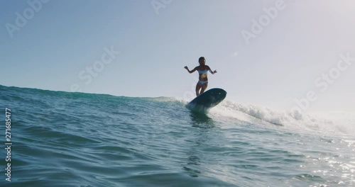 Young woman surfing in slow motion on summer wave, doing amazing longboard turn in slow motion, summer surf vacation