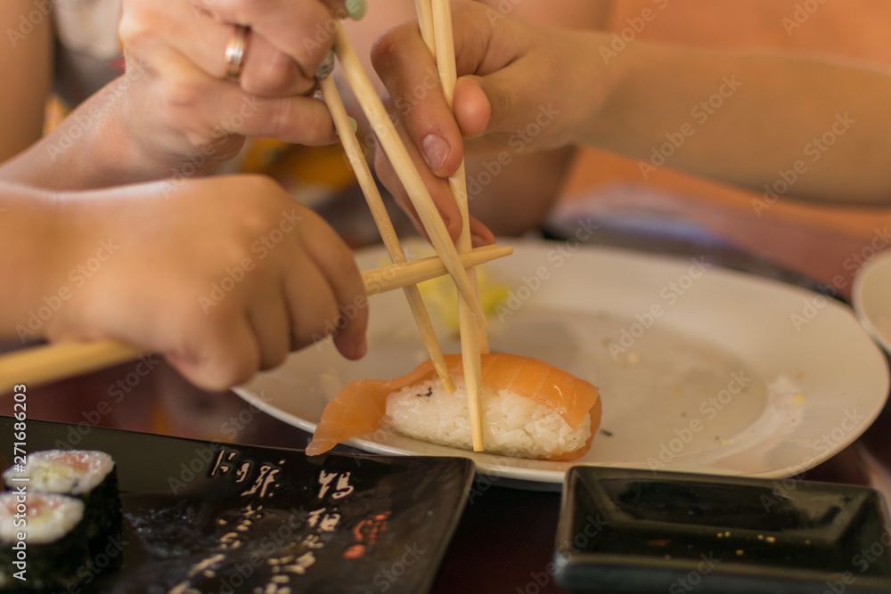Fototapeta premium A hand with chopsticks takes sushi.