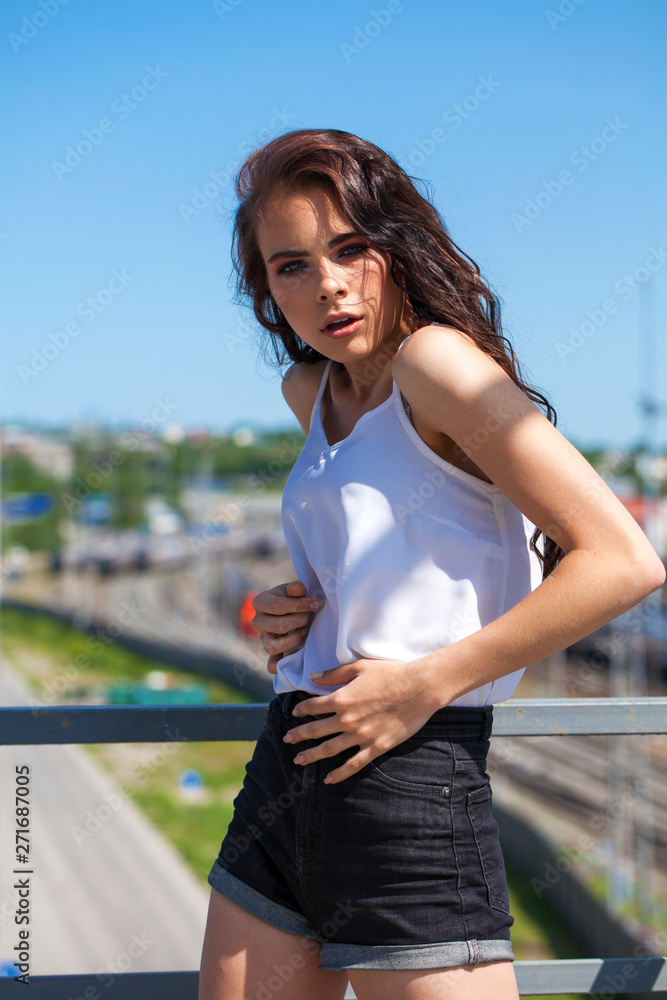 Pretty young brunette model in white summer blouse and jeans, summer street outdoors Pretty young brunette model in white summer blouse and jeans, summer street outdoors