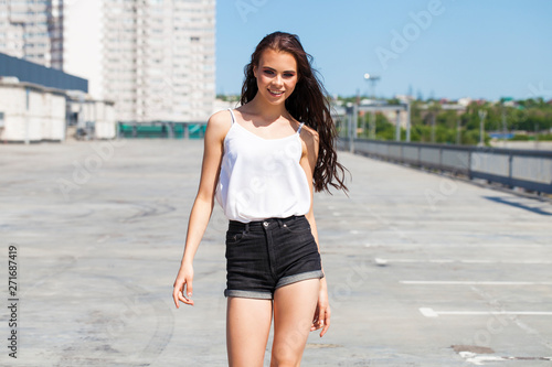 Pretty young brunette model in white summer blouse and jeans, summer street outdoors