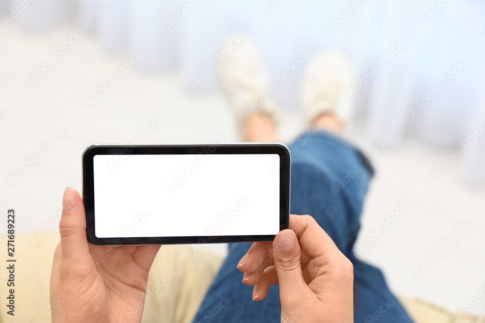 Woman holding smartphone with blank screen indoors, closeup of hands. Space for text