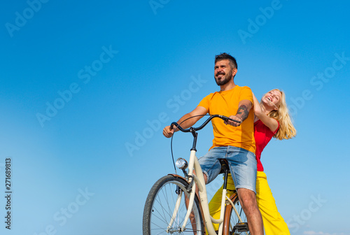 Young riders enjoying themselves on trip. Stylish and loving couple enjoying. Couple in love riding a bike. Attractive couple on a bike ride on a sunny day. Couple with vintage bike.