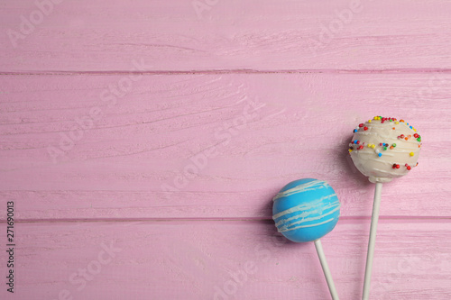 Bright delicious cake pops on wooden table, flat lay. Space for text