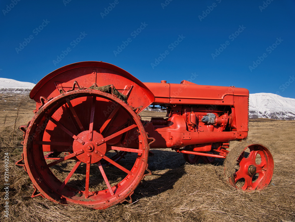 Ein Oldtimer Traktor im Feld vor einer Bergkulisse