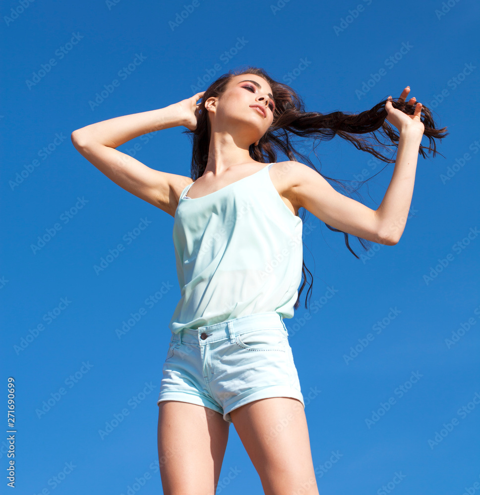Young beautiful woman in a turquoise blouse posing against the blue sky Young beautiful woman in a turquoise blouse posing against the blue sky