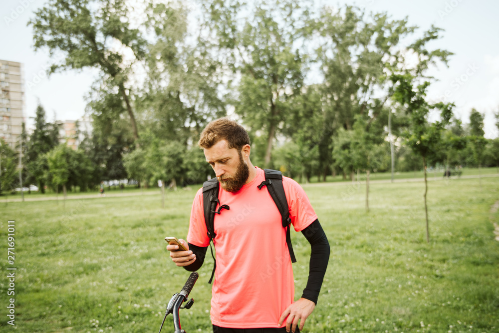 Fototapeta premium Cyclist in the park. Phone and bicycle