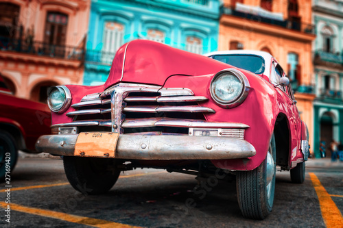 Old car painted hot pink and colorful buildings in Havana © kmiragaya