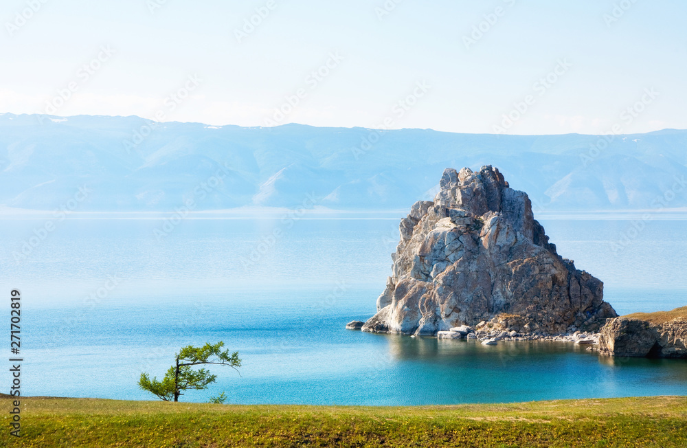 Baikal Lake in summer. View of the natural landmark of Olkhon Island - Shamanka Rock at June afternoon. Lake natural background. Beautiful landscape. Place for text