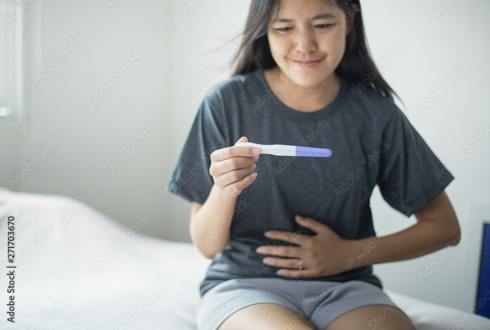 Asian female hand touching her belly after testing pregnancy test at home Asian female hand touching her belly after testing pregnancy test at home