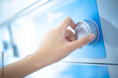 Close up hand is turning dial knob of laundry washing machine