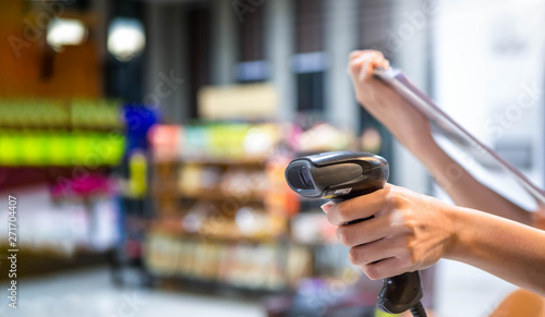 Close up barcode scanner in hand on blurred background,Inspection of goods in the warehouse,The concept of selling products in a supermarket,Spot focus,Copy space.