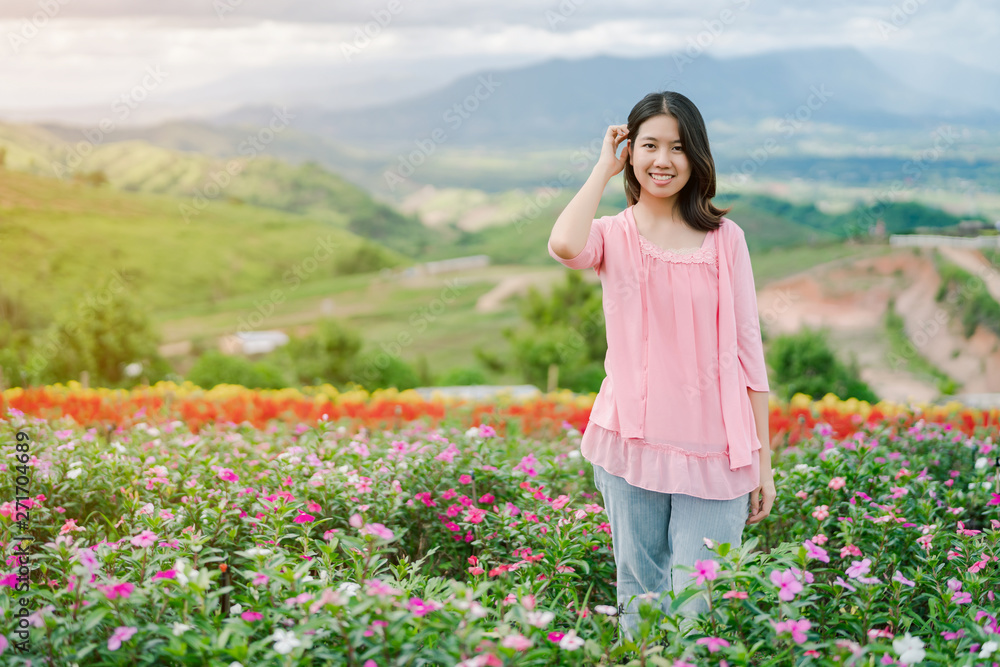 Asian beautiful woman Wearing a pink shirt Smiling happily in the pink flower garden Behind is a mountain view Asian beautiful woman Wearing a pink shirt Smiling happily in the pink flower garden Behind is a mountain view