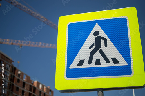 road sign pedestrian crossing against the sky and building