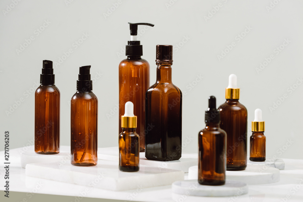 Spa cosmetics in brown glass bottles on gray concrete table. Copy space for text. Beauty blogger, salon therapy, branding mockup, minimalism concept Spa cosmetics in brown glass bottles on gray concrete table. Copy space for text. Beauty blogger, salon therapy, branding mockup, minimalism concept