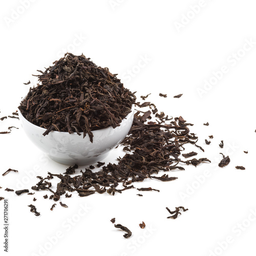 Dried tea leaves in ceramic cup over white background.