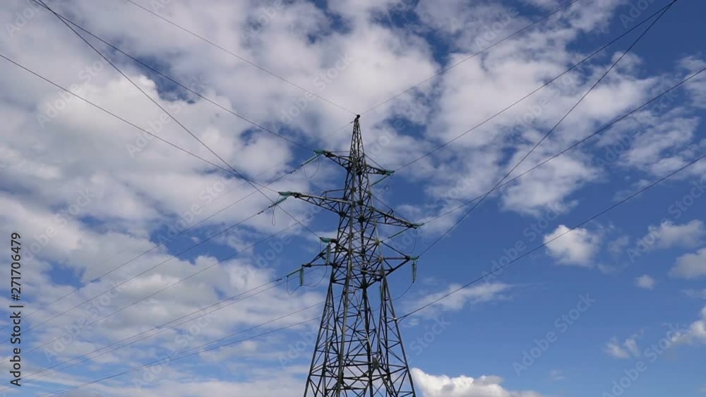 Power lines against the sky with clouds. High voltage line and power pylons on a sunny day with the blue sky. Time laps. Power lines against the sky with clouds. High voltage line and power pylons on a sunny day with the blue sky. Time laps.