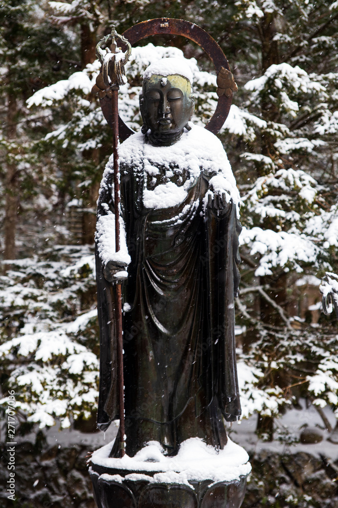 Standing Buddha under the snow in Okunoin Cemetery, Koyasan area in the mount Koya region, UNESCO World Heritage area, Wakayama Prefecture,  Japan.