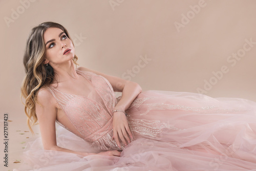 Photographie sensual woman in lace evening dress laying on the beige background