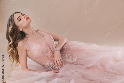 Fotografering sensual woman in lace evening dress laying on the beige background