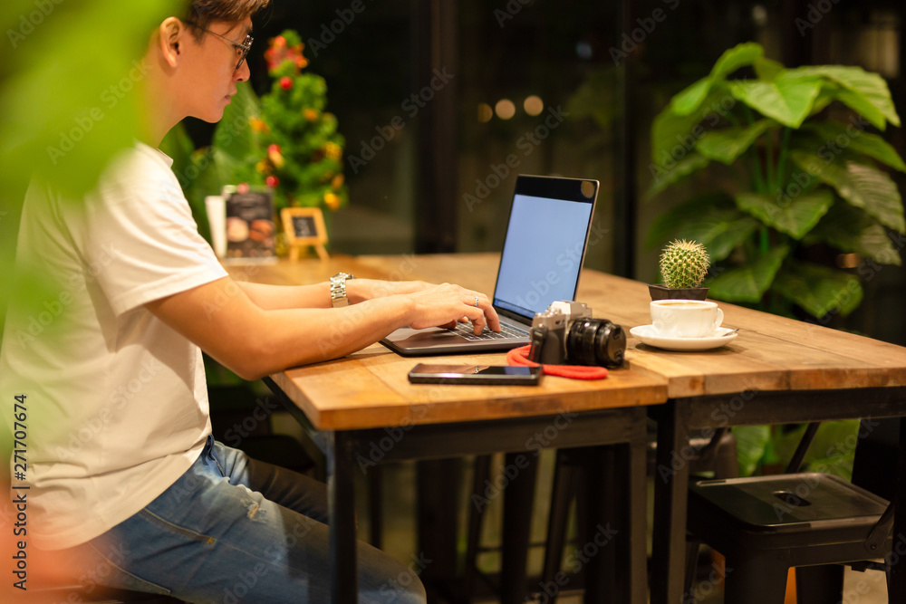 Male freelancer working on laptop at late night in coffee shop. Male freelancer working on laptop at late night in coffee shop.