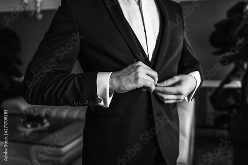 Man in business suit. A man puts on a suit. Close-up business stylish man buttoning his jacket. A businessman in an expensive suit. Black and white photo