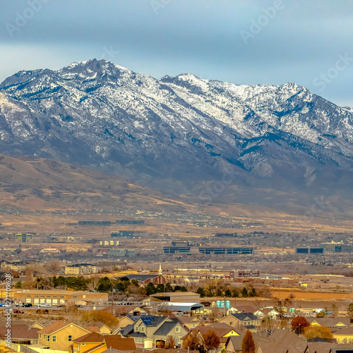 Frame Square Panorama of a snow capped mountain towering over houses in the vast valley