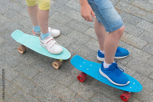 against the stone paving, close-up, two skateboards with the feet of a boy and a girl on them
