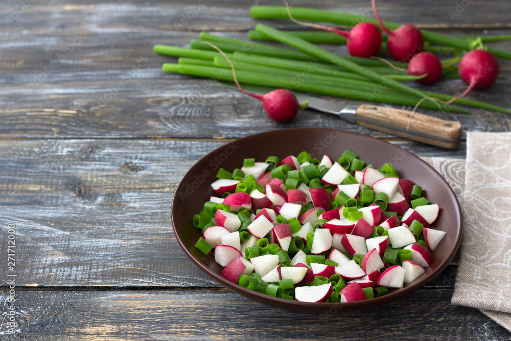 Fresh radish salad with green onions on a wooden background, rustic style Fresh radish salad with green onions on a wooden background, rustic style