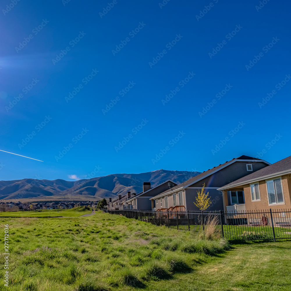 Square Houses on a lush grassy field under the blazing sun and vivid blue sky Square Houses on a lush grassy field under the blazing sun and vivid blue sky